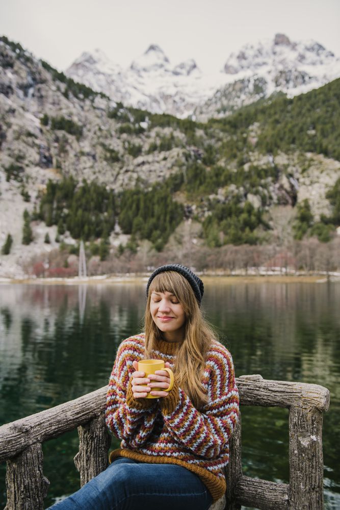 Woman on seat near wonderful lake between hills in snow