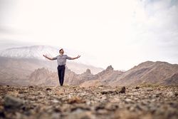 man with outstretched arms in mountains
