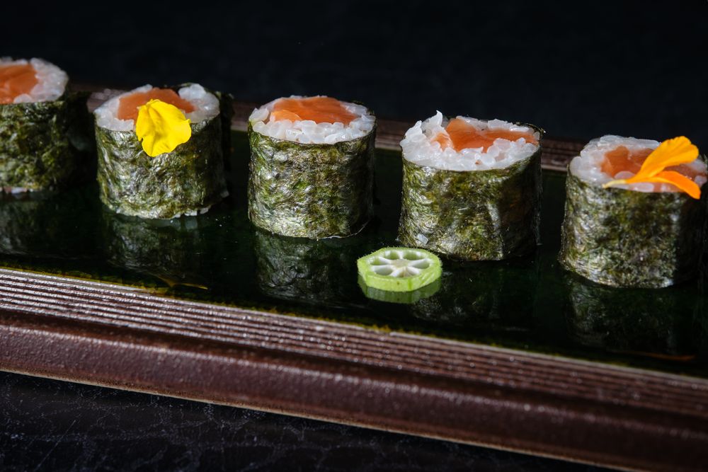 Delicious sushi rolls with salmon served on wooden tray