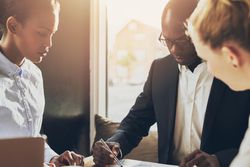 Three businesspeople heads down focused on documents