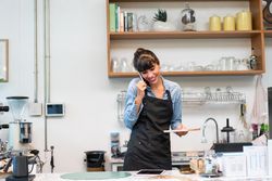 Smiling woman on phone in cafe writing down order
