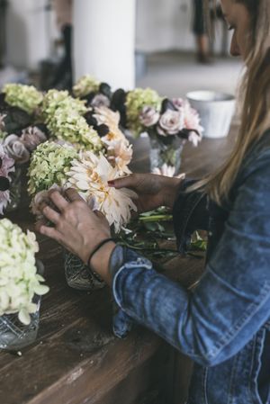 Woman near table with bouquets of blooms in vases