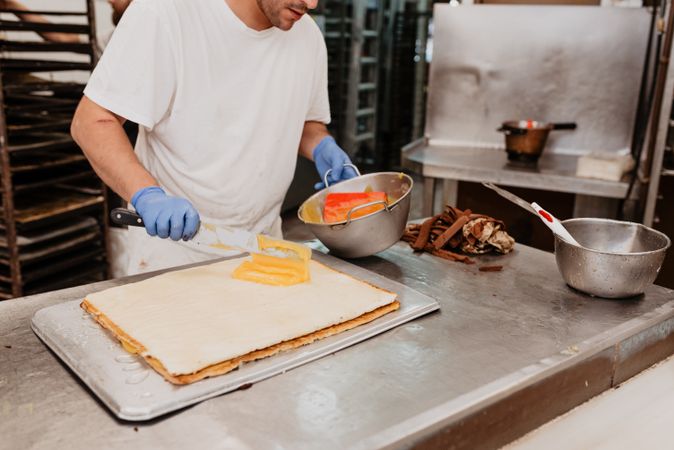 Crop confectioner smearing jam on croissant