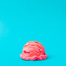 Scoop of pink ice cream on bright blue background
