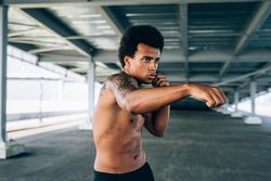 Black male athlete doing intense boxing training under a bridge