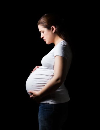 Beautiful expectant pregnant woman looking her belly isolated