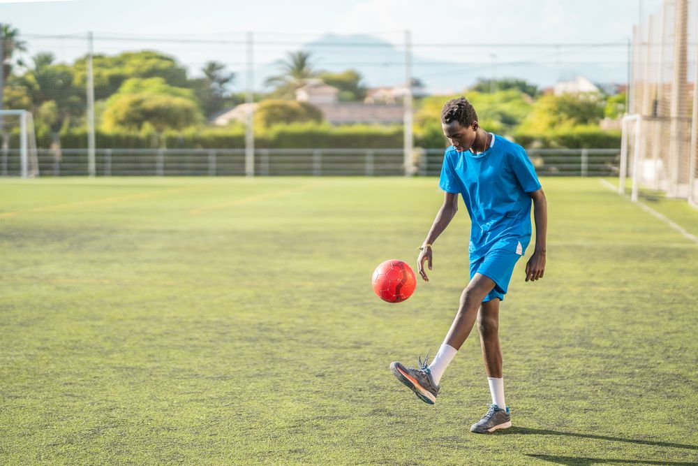 Black teenager juggling football ball