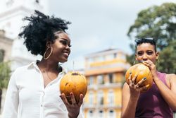 Latin American women having fun in the city drinking coconuts