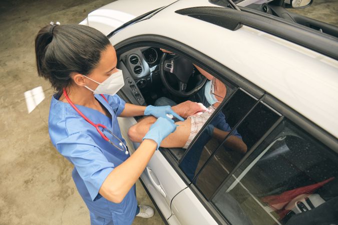Nurse injecting COVID 19 vaccine into arm of crop driver