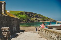 People sitting on a wall leading to a beach