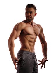 Bodybuilder practicing side poses ahead of competition in bright studio