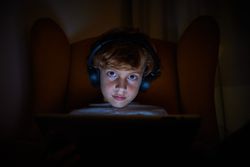 Boy using tablet in dark living room