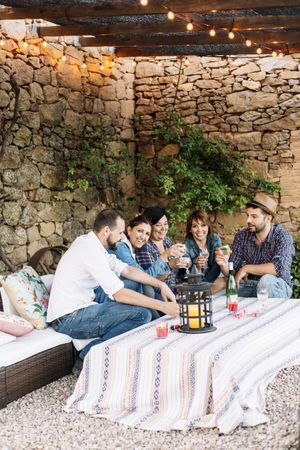 Happy group of friends sitting together and laughing while enjoying wine at a party