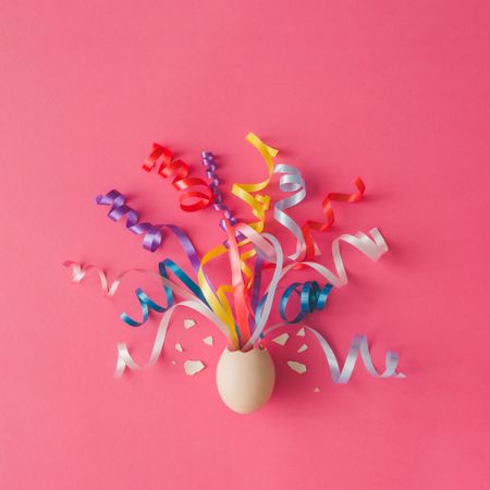 Egg with party streamers on pink background