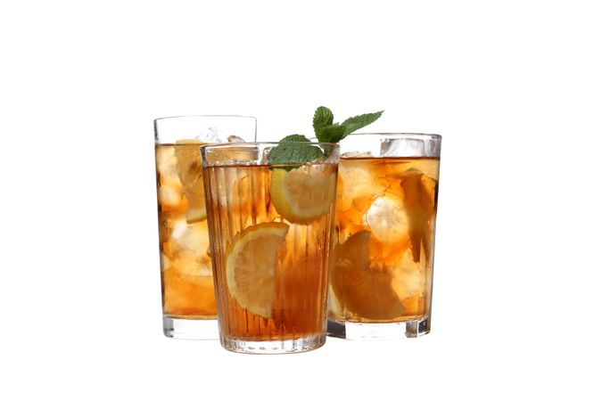 Glasses of cold tea with orange and ginger, isolated on plain background