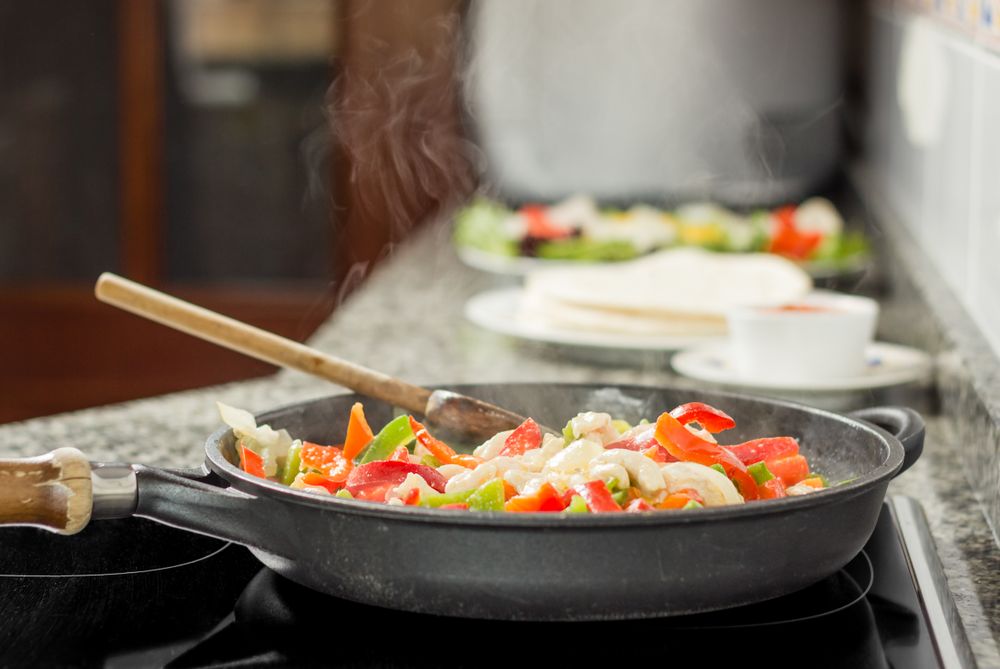 Pan cooking vegetables and chicken in the kitchen