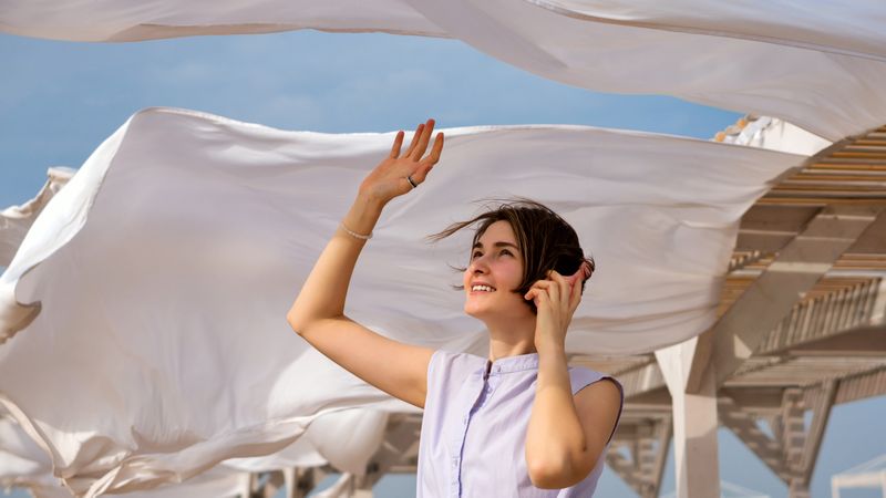 Woman listens to music with headphones outdoors