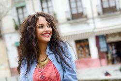Happy female with curly hair standing on balcony outside