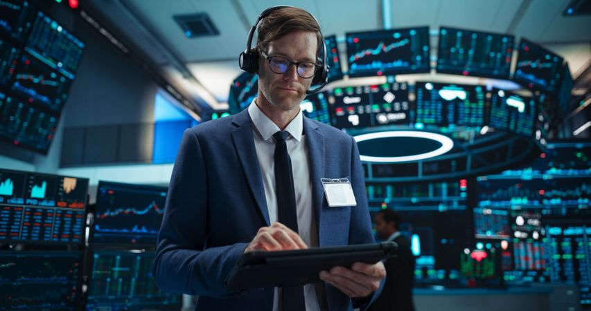 Portrait of a Stock Exchange Broker Using Tablet Computer, Researching Real-Time Stocks Data, Analyzing Commodities and Exchange Market Charts.