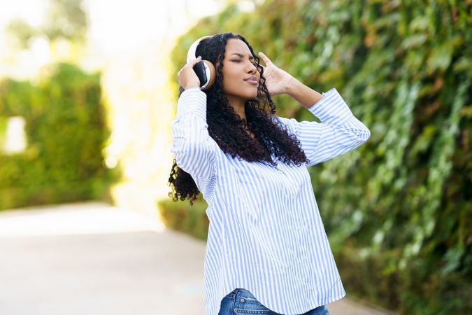 A young woman is completely immersed in enjoying music outdoors while wearing headphones