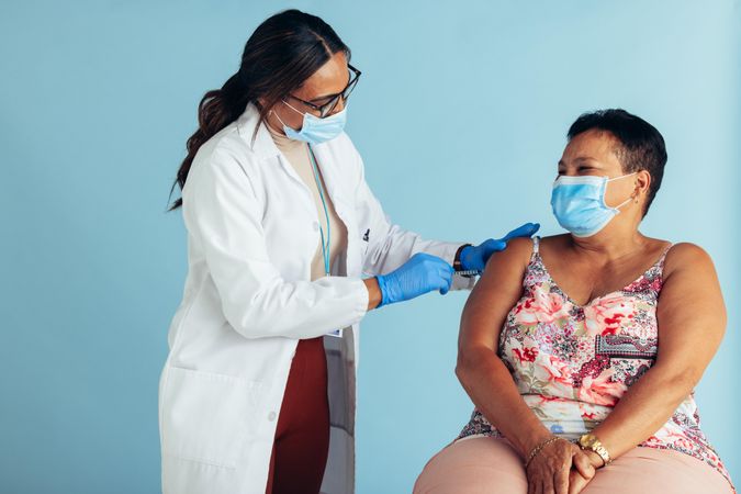 Healthcare professional giving vaccination to older woman
