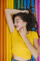 Cheerful woman lying down on rainbow bench back ground