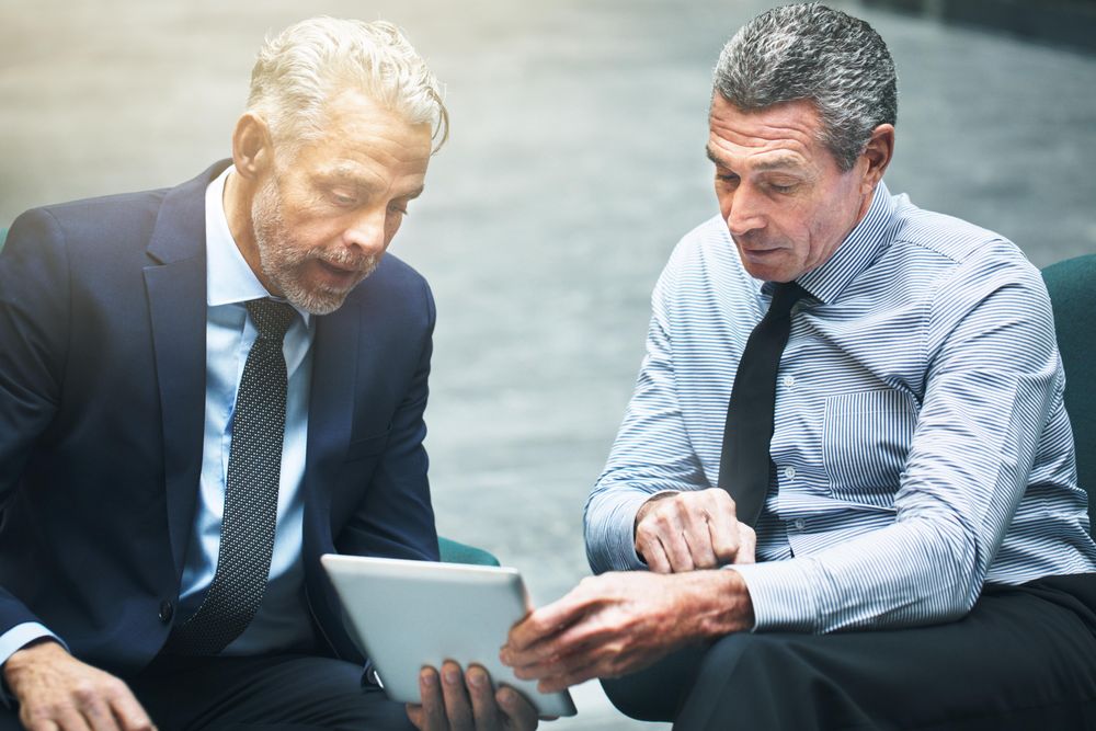 Two professional men discussing work with a tablet