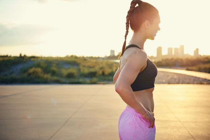 Athletic woman standing in morning sun with city in background