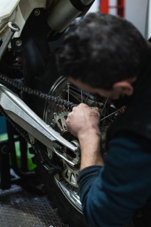 Unrecognizable mechanic repairing motorcycle in garage