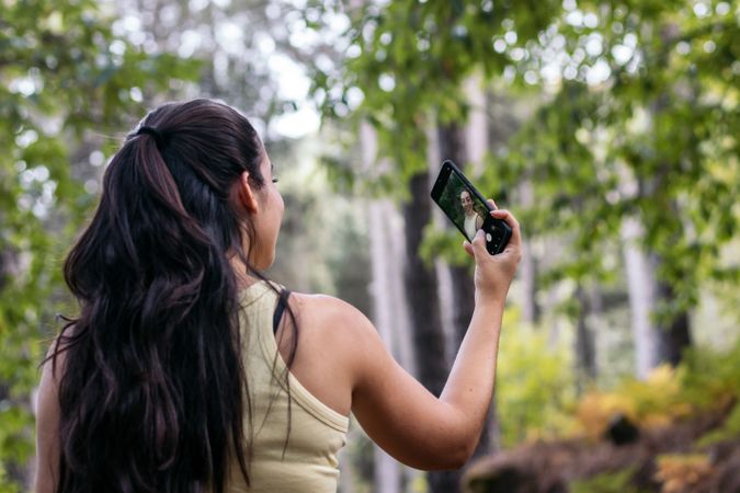 Young woman taking selfies with smartphone in the forest
