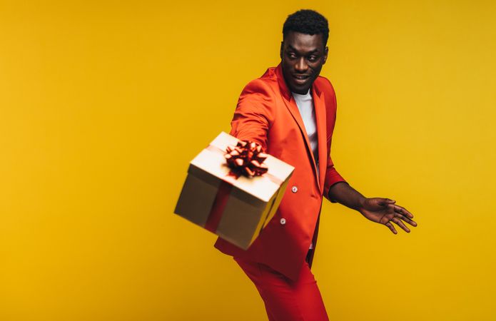 Black man giving a gift over yellow background