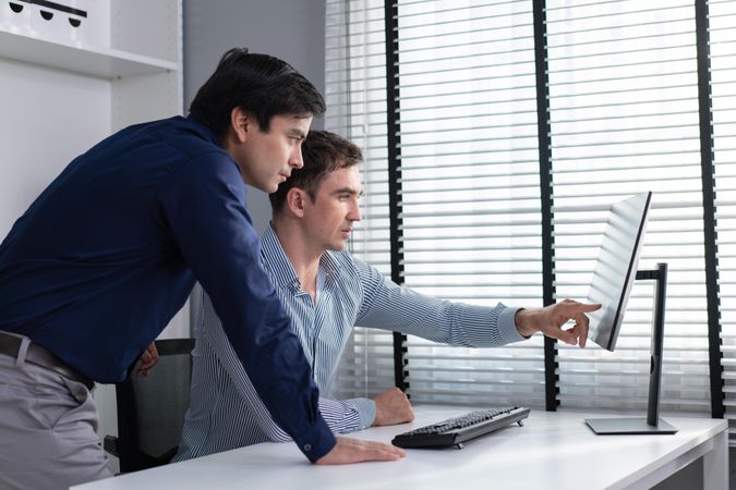 Corporate colleagues talking together over screen in the workplace