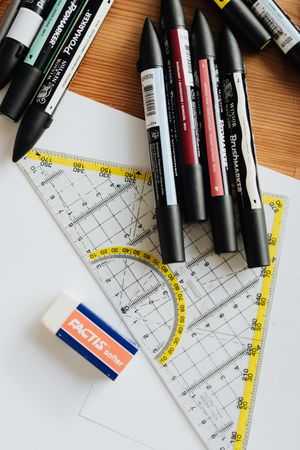 Set square ruler and markers on wooden table