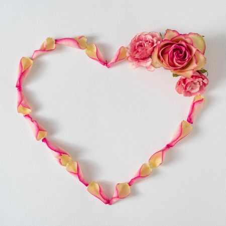 Heart shape made of rose petals and pink flowers