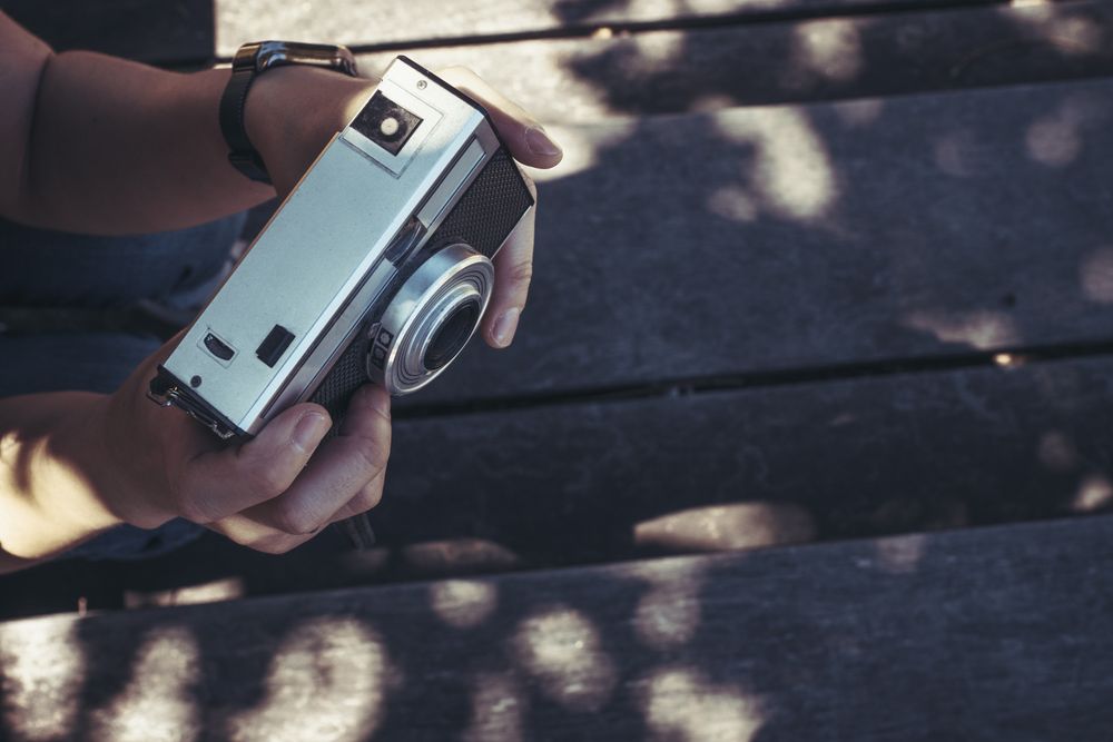 Woman with photo camera sitting and looking along in sunny day