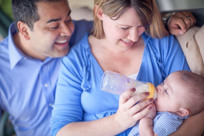 Happy Couple Bottle Feeding Their Son.