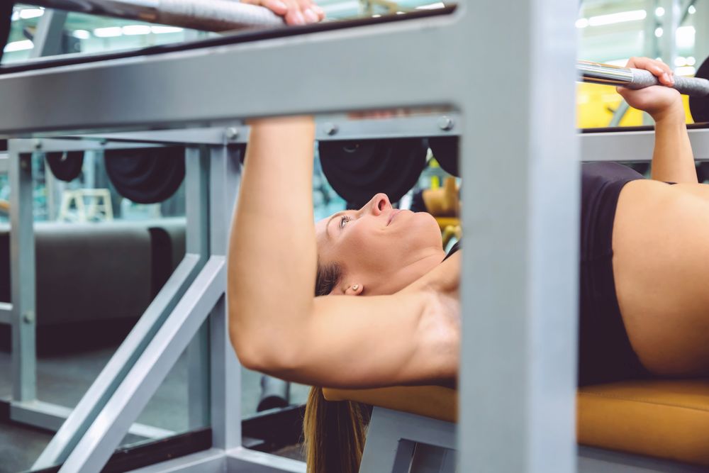 Close up of woman doing bench press in gym
