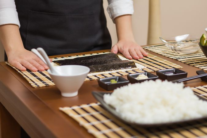 Chef ready to prepare Japanese sushi rolls, with principal ingredients in the foreground