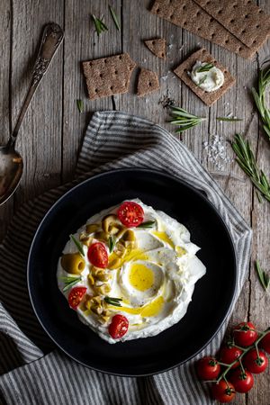 Crackers and herbs near plate with labneh