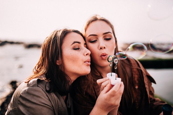 Two young women blowing bubbles outside