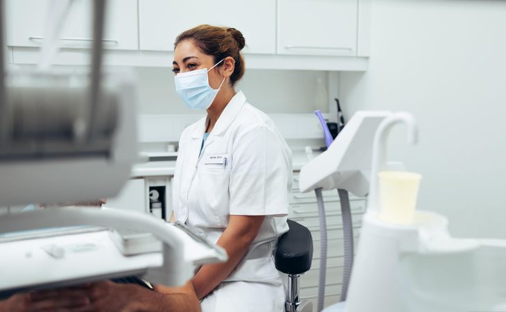 Female dentist sitting in a chair beside male patient