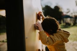 A young child on a rock climbing wall outside