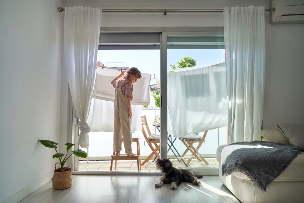 Kid hanging linen on clothesline at home