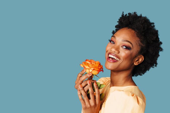 Studio shot of a joyful Black woman with a yellow rose