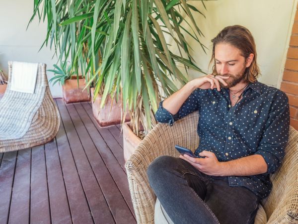 Trendy handsome male with phone on terrace