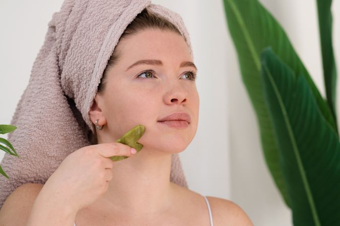 Woman performing facial massage with gua sha