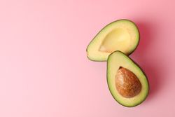Ripe fresh avocado on pink background, top view