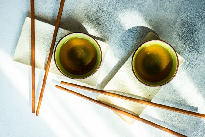 Top view of two cups of green tea and chopsticks