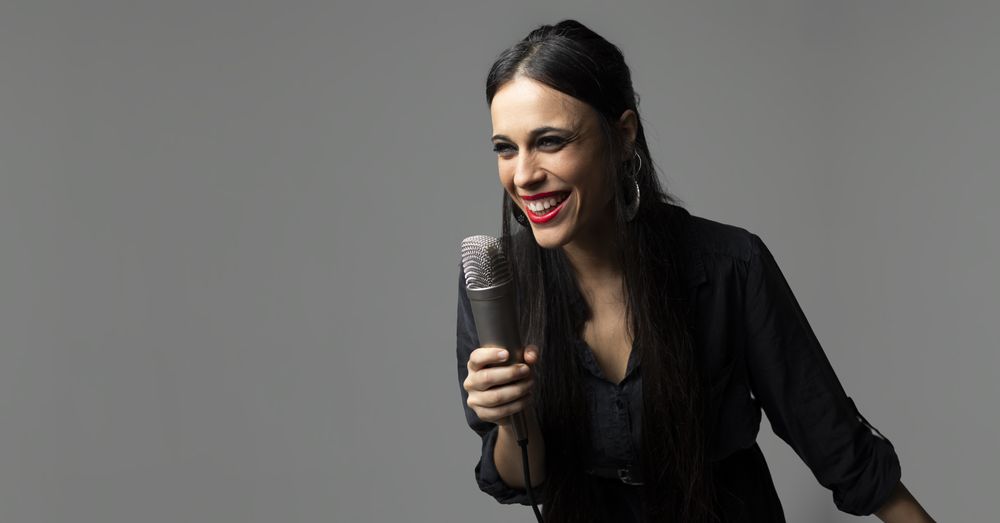 A young female singer, sings with a microphone in her hand while smiling