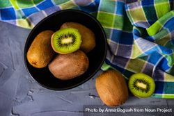 Bowl of kiwi fruits with one halved on top 5r9D8p